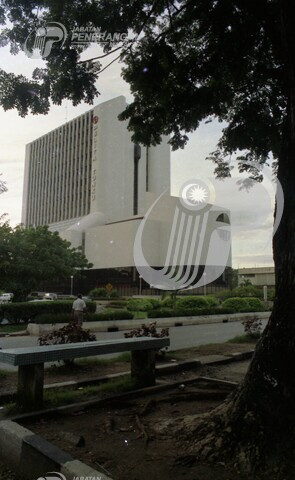 Then: An image from under some trees showing the front and right sides of the tower.
				Curvatuous and white with dark grey stripes running up the "tower" bit on top (simulating ribbon windows) of the "mall" bit on the bottom.
				Mall bit has wraparound glass walls which reach up two floors, and an inset walkway.
				A glass bubble lift is visible going up the side of the tower going up a thin dark grey inset stripe.