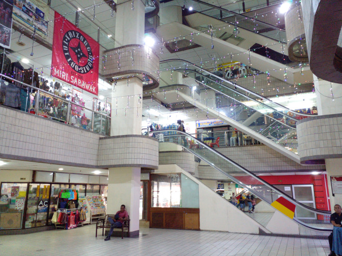 Now: instead of colourful banners there's now one big red square one, advertising the "Taizong Tatoo Studio, est. 2010", 
				hanging from the railings on the second floor. The side of the hair salon booth is visible: it seems to be glossed wood up to waist level, then windows above up to
				just under the escalators where it becomes painted white plywood. The Sugarbun is a bit smaller;
				it extended all the way left where there's now what I think is a staitonary shop.